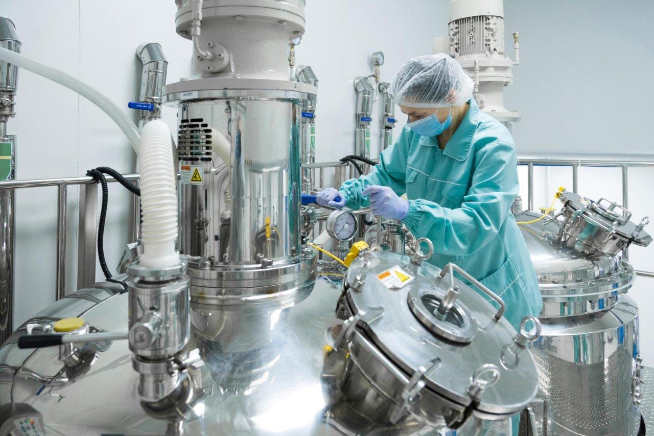 Technician beside stainless-steel process equipment